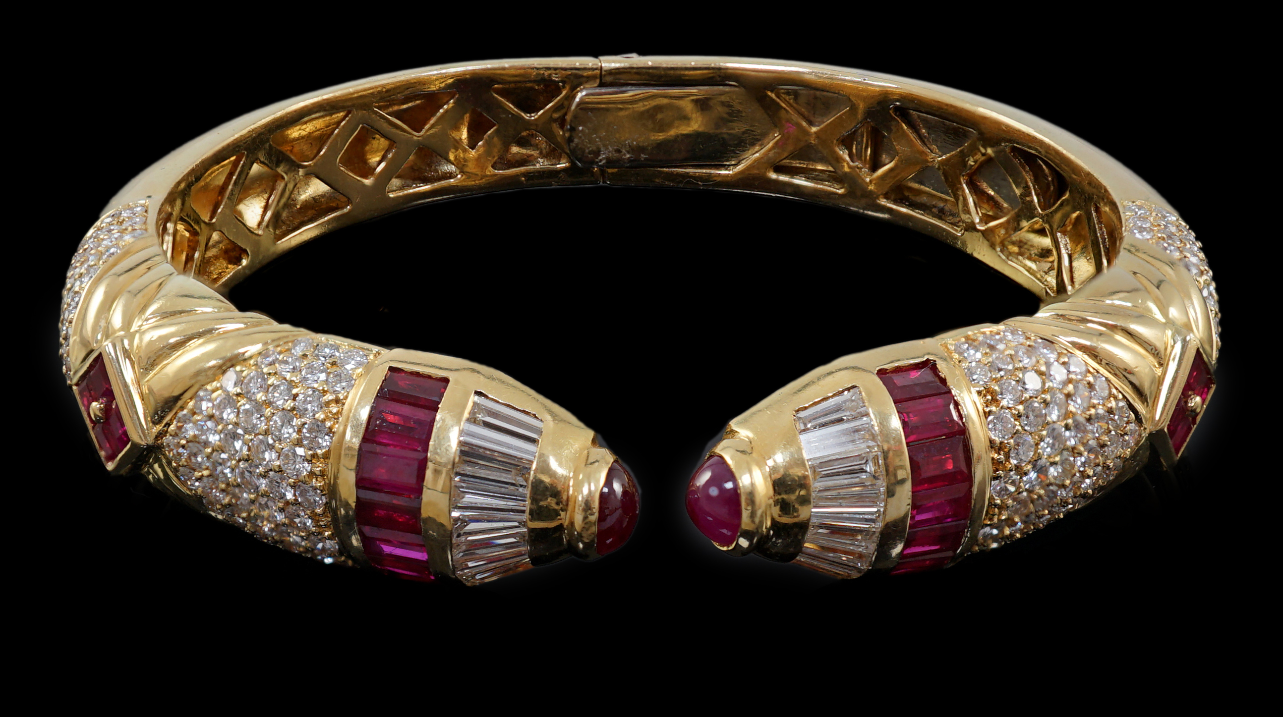 A modern 18ct gold, ruby and diamond cluster openwork hinged bangle